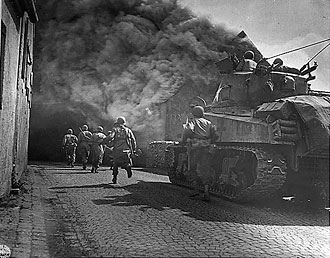 file:/activities/oralhistory/cappics/cohen1944_tank, alt: Tank and American soldiers charging down a street of Wernberg, Germany