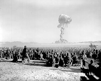 file:/activities/oralhistory/cappics/elliot1945_detonation, alt: thousands of sitting soldiers watch a mushroom cloud in the distance
