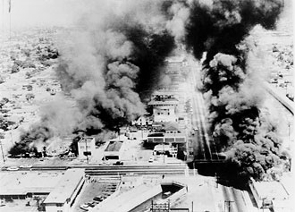 file:/activities/oralhistory/cappics/elliot1945_watts, alt: an aerial view of several burning buildings